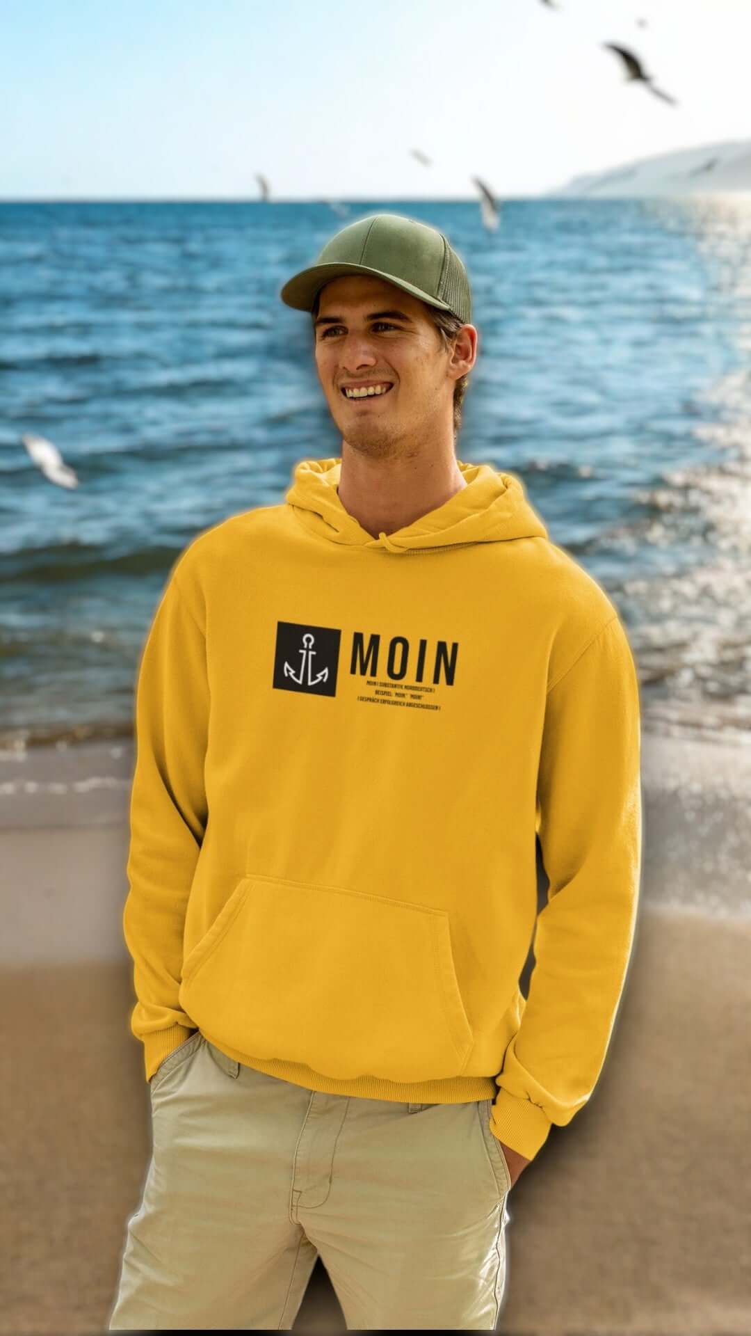 junger-mann-am-strand-im-gelben-moin-hoodie